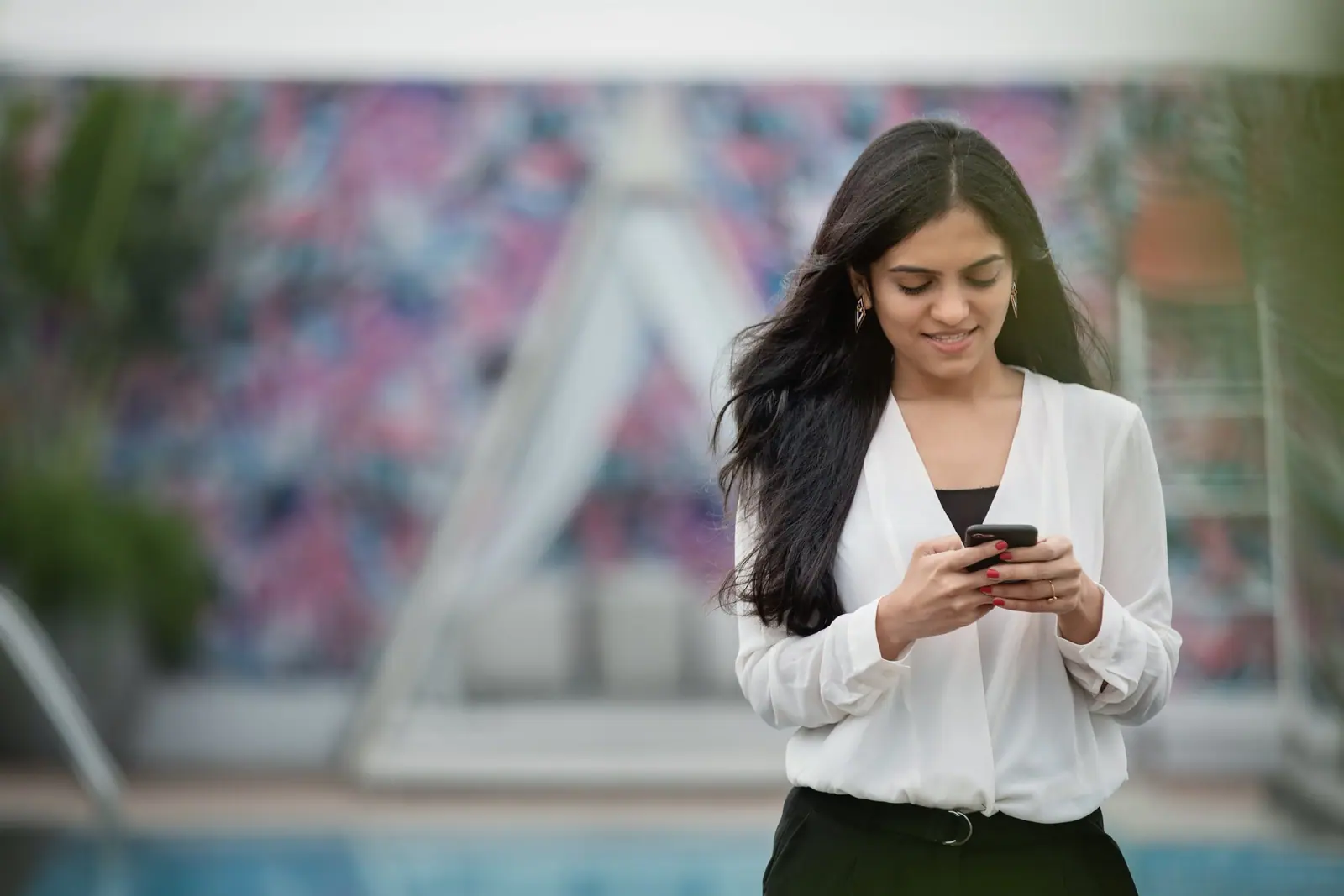 Mulher sorrindo enquanto olha o celular (imagem ilustrativa)